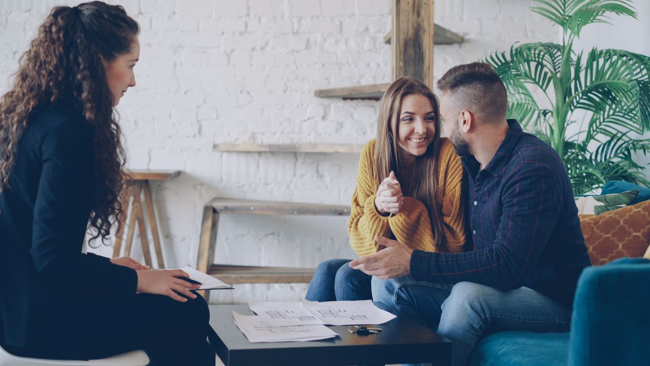 Services Smiling couple discussing real estate plans with advisor in modern, cozy setting.